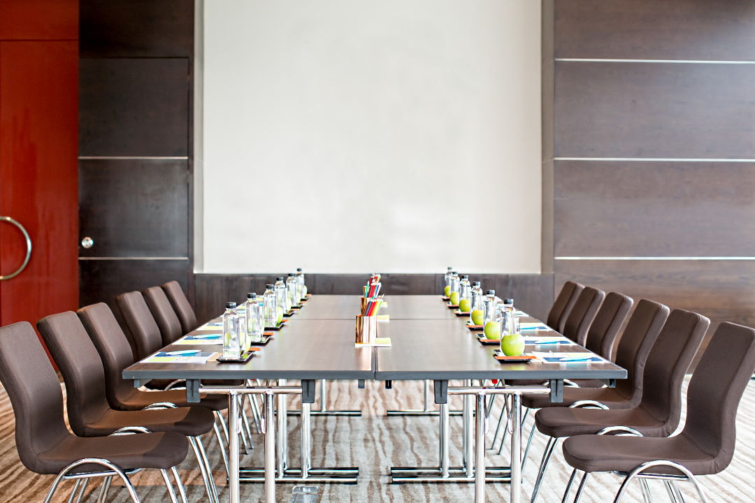 Empty meeting room with conference table, whiteboard and chairs. Front view.